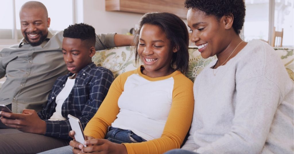 happy parents and teens looking at phones