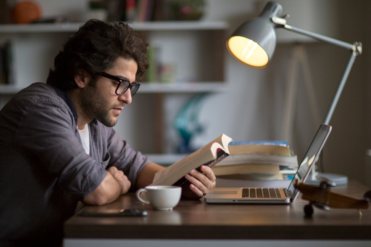 A young man sitting in front of his computer reading Samson and the Pirate Monks.