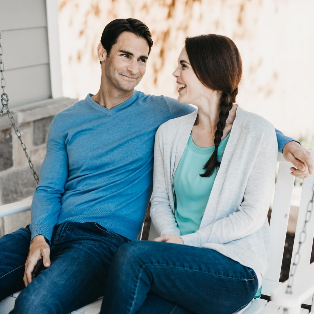 married couple smiling while on porch swing