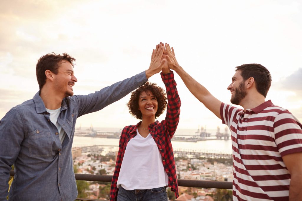 A husband and wife with a friend, high-fiving.