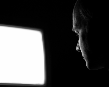 man looking at computer in dark room