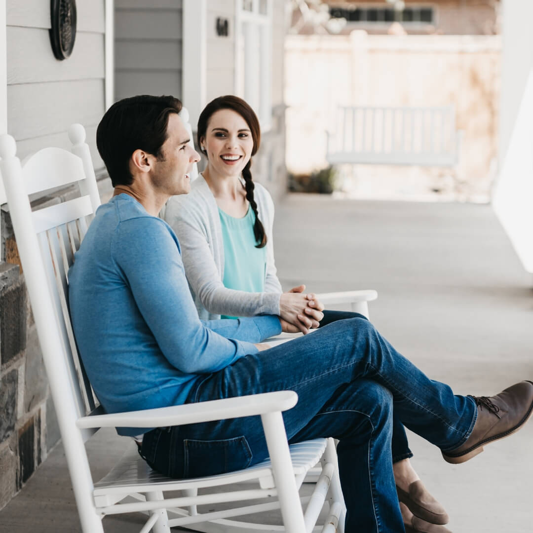 couple smiling and talking on front porch
