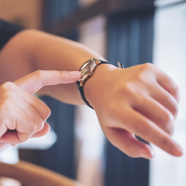 woman pointing at wrist watch