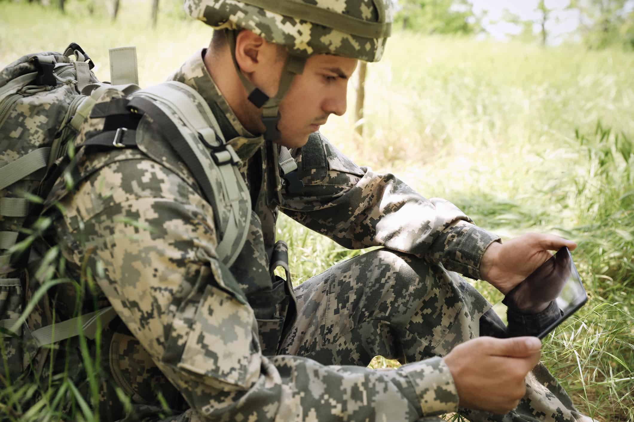 A solider in the forest with a tablet.