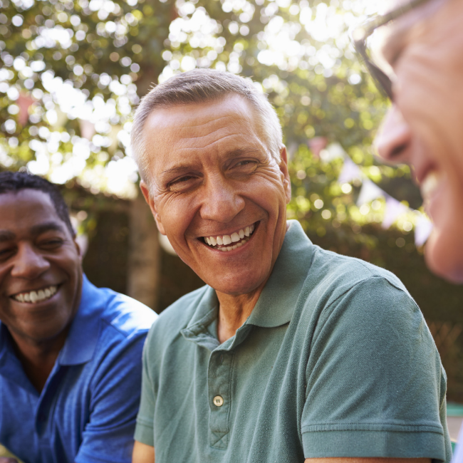 three middle age men laughing together outside