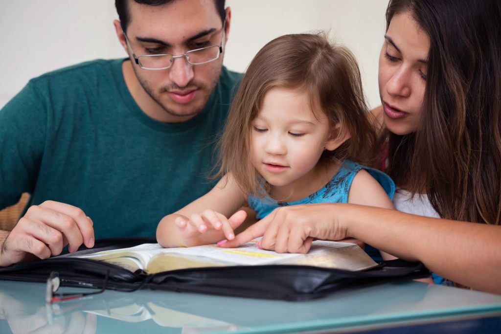 Parents teaching their children the Bible.