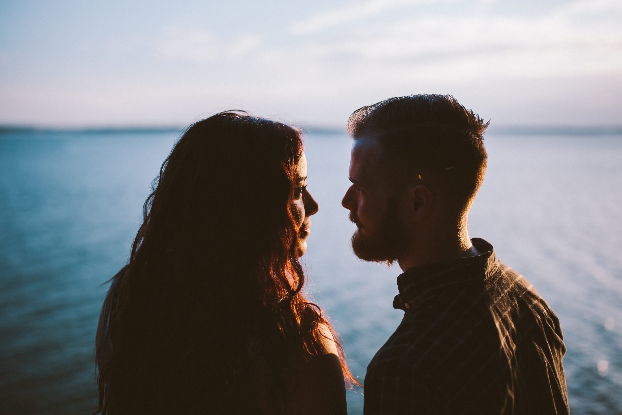 young couple staring at each other by water