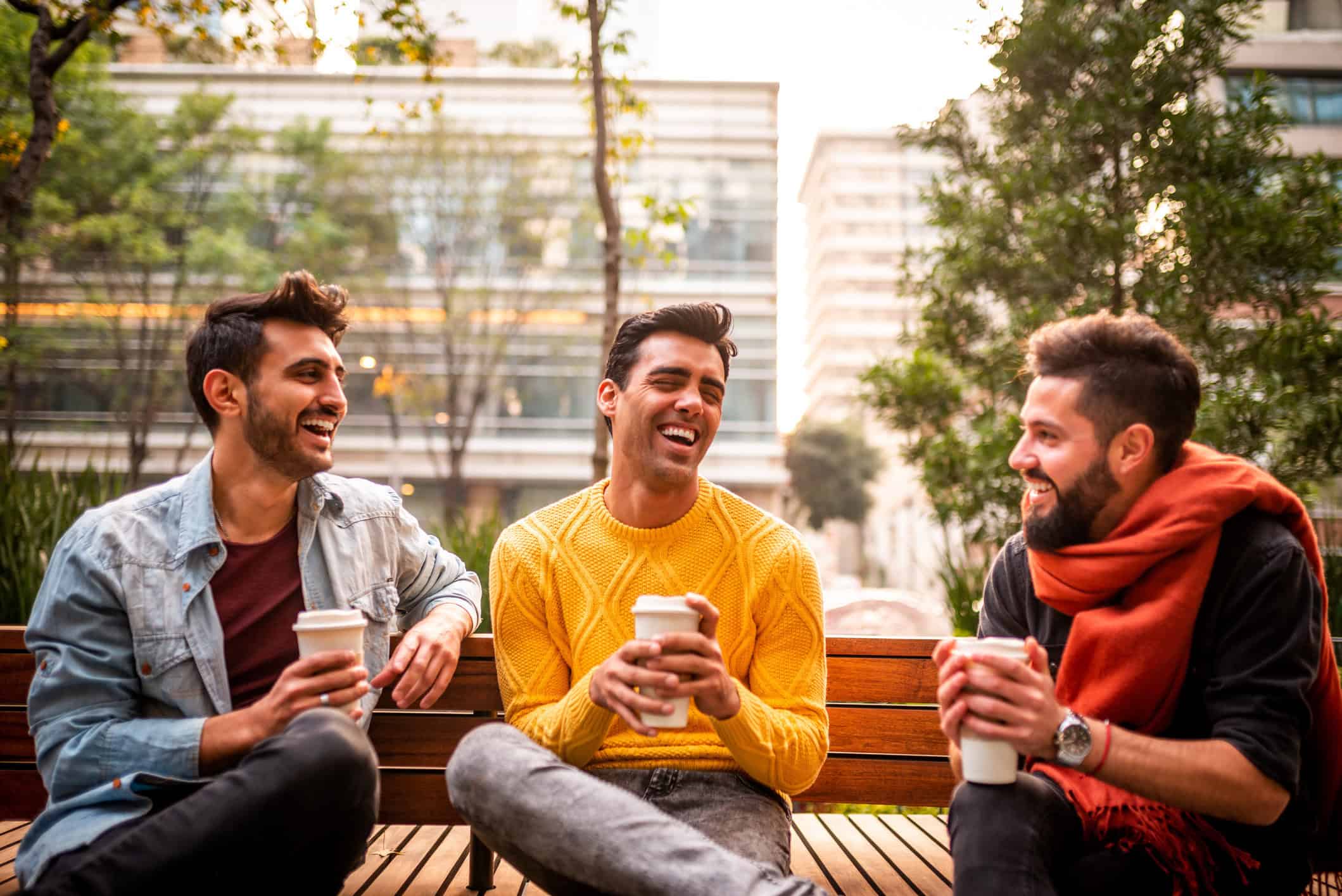 Three guys enjoying coffee outside.
