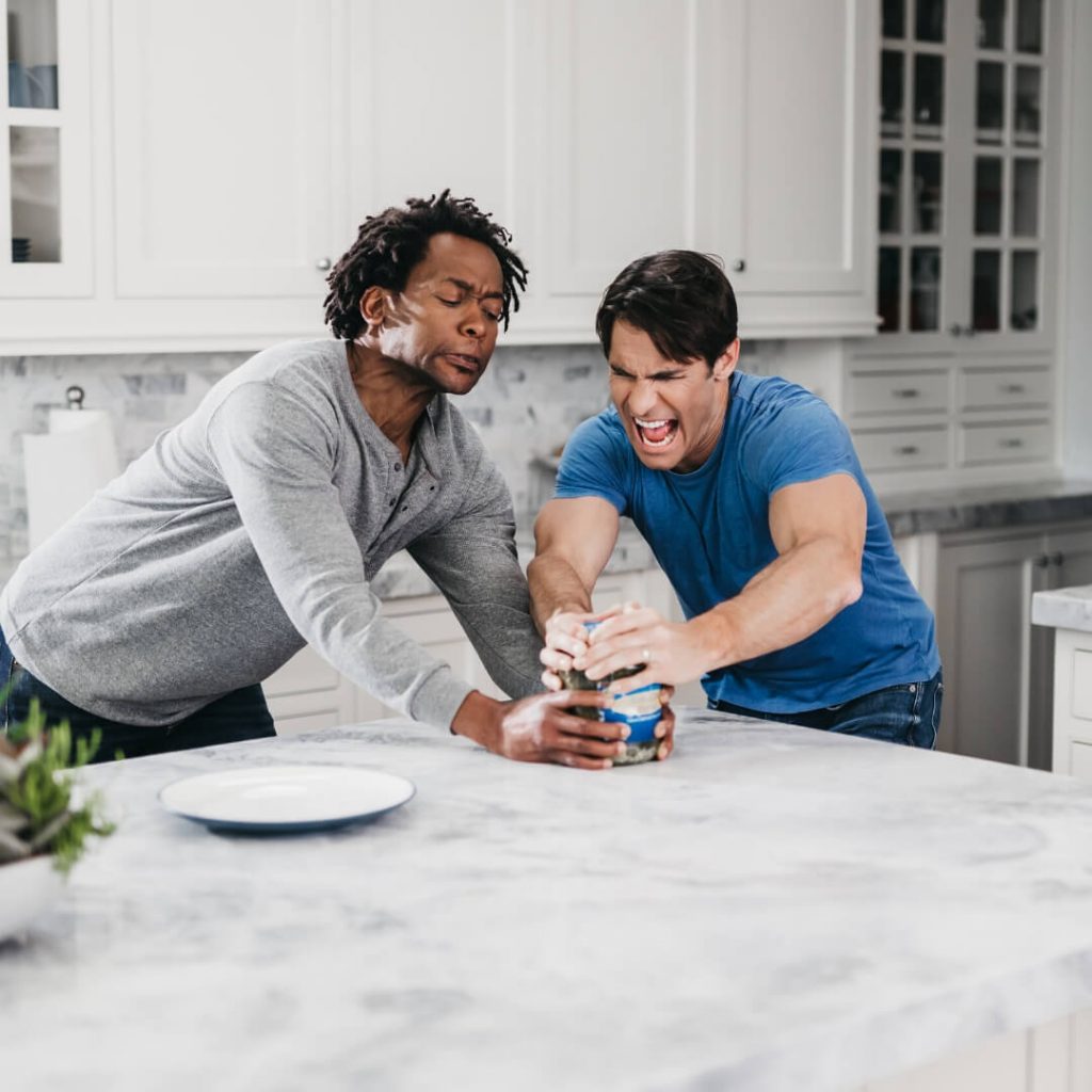 two men trying to open jar of pickles