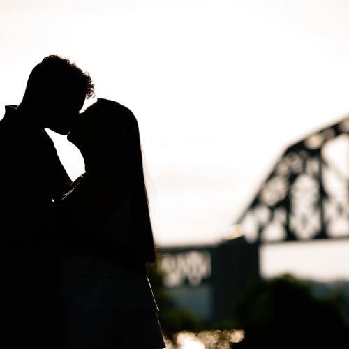couple kissing outside by bridge