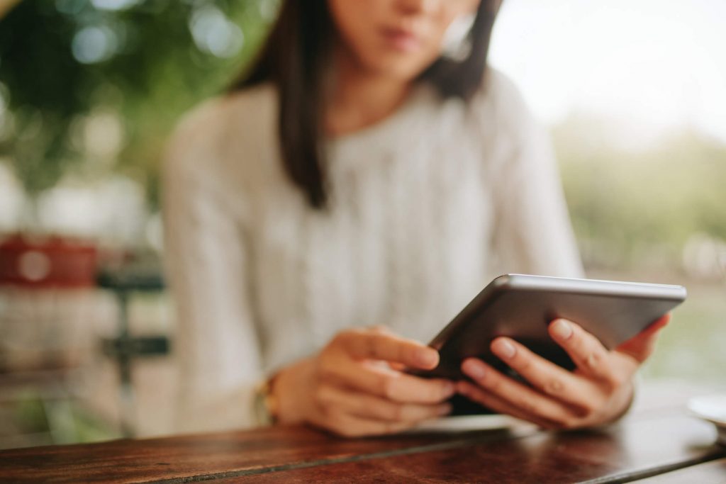 burry image of a woman reading a tablet outside