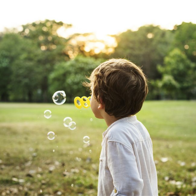 boy blowing bubbles in field