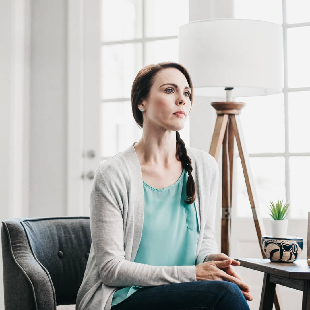 distraught looking woman sitting on living room chair