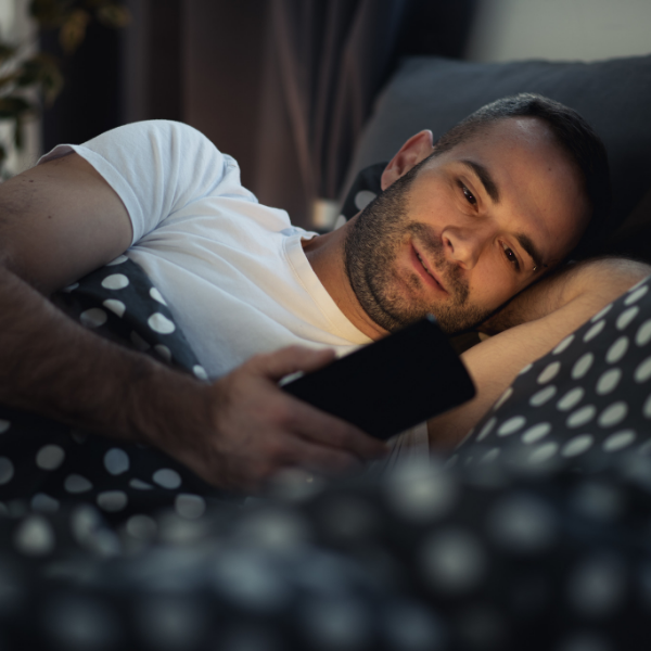 man looking at phone in bed