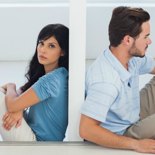 Sitting couple are separated by wall with woman looking at camera