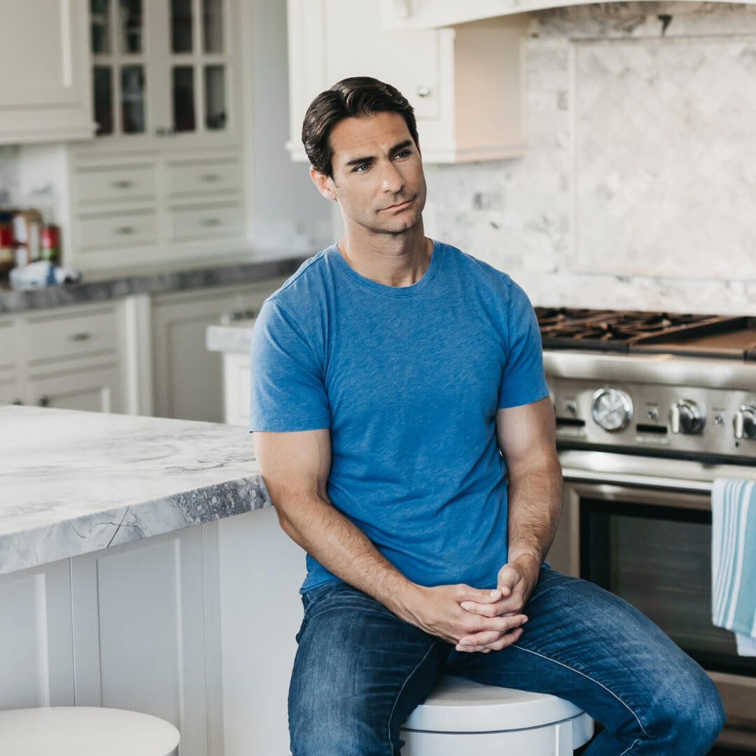 man with pensive face sitting alone in kitchen