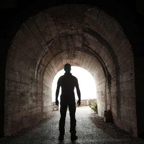 man standing in dark archway