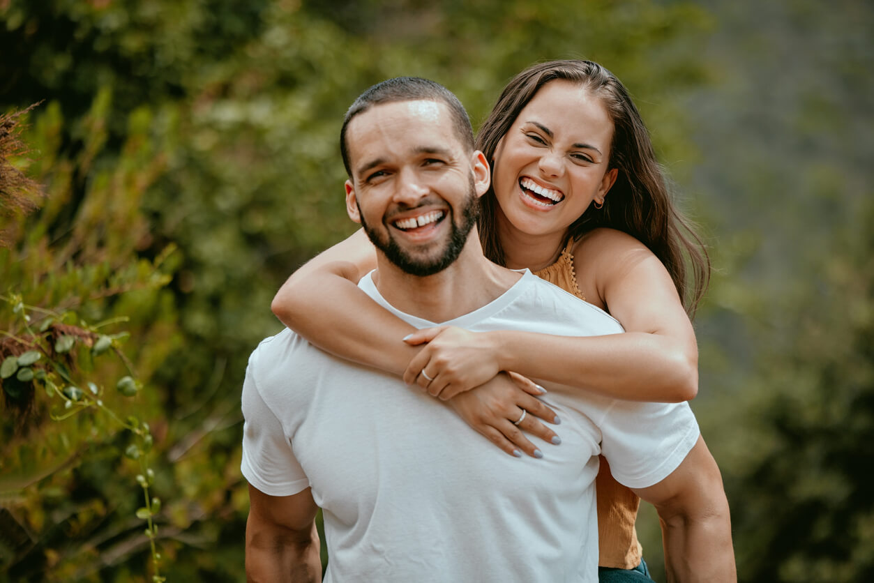 Smiling couple embracing, enjoying the outdoors.