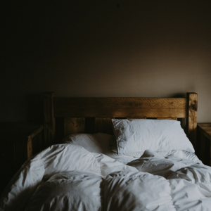 unmade bed with wood headboard