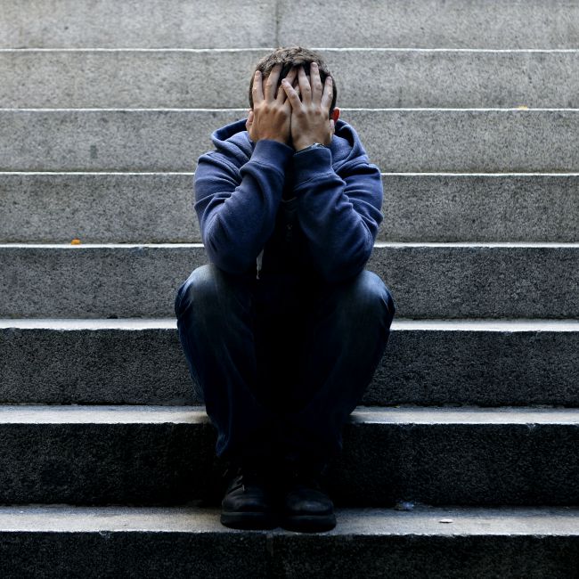 man sitting on stairs with head in hands