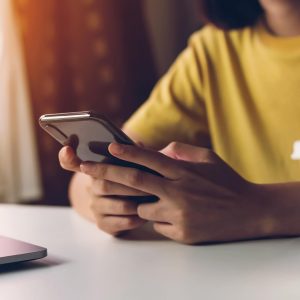 woman in yellow shirt texting on her phone