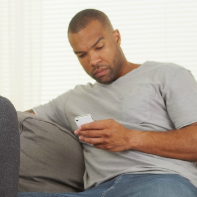 grumpy man on phone on couch