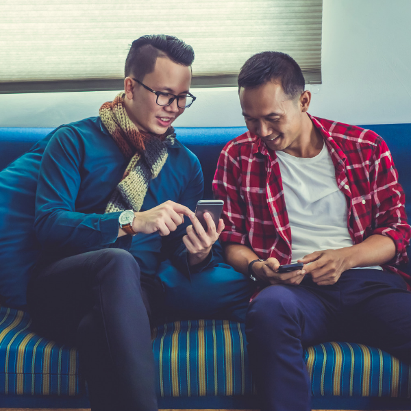 two friends looking at phone on couch