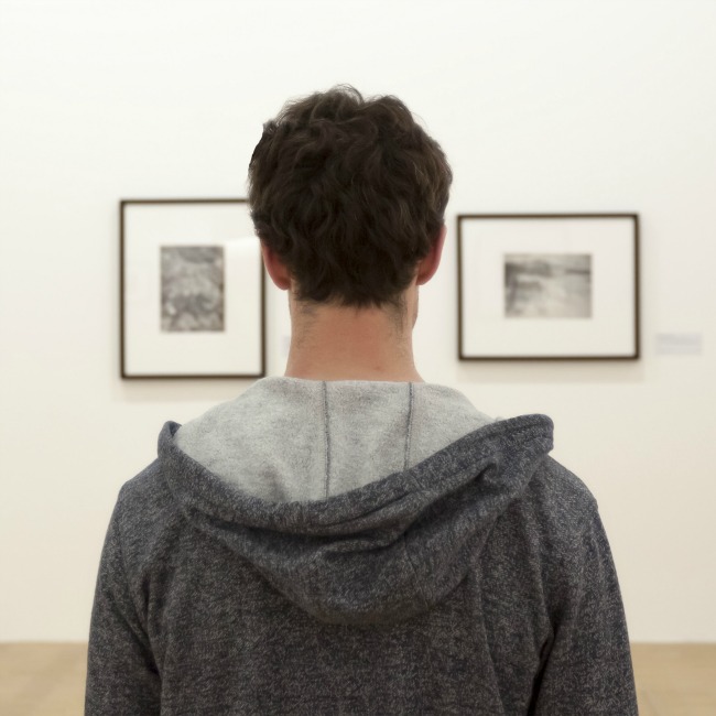 young man staring at art in museum
