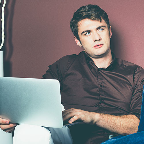 man thinking as he uses laptop