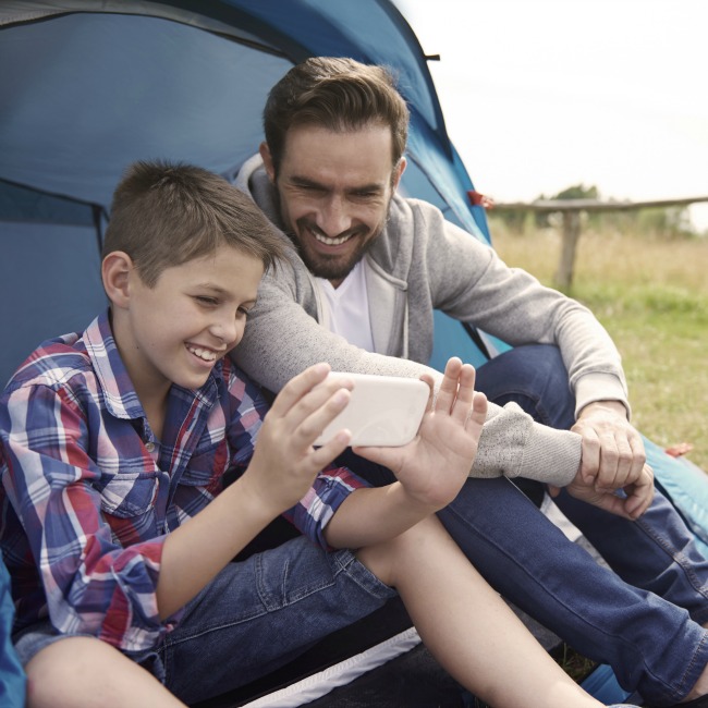 boy on phone with dad while camping