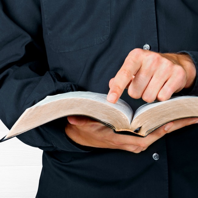 man pointing to open bible