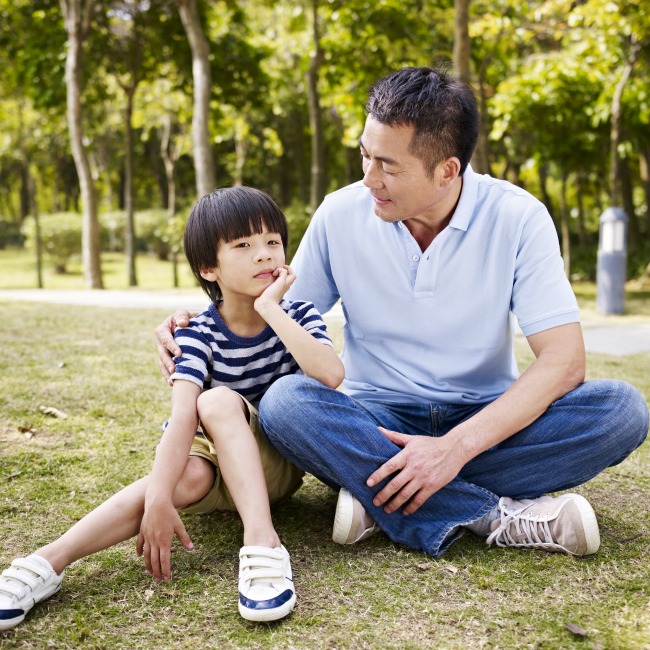 dad and young son talking in park
