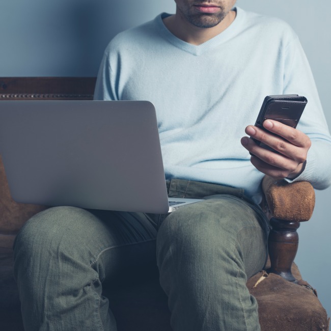 man on computer and phone