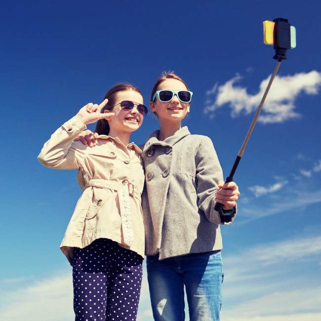 two girls taking selfie with selfie stick
