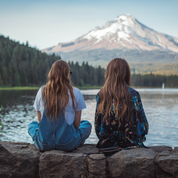 two girls sitting by lake