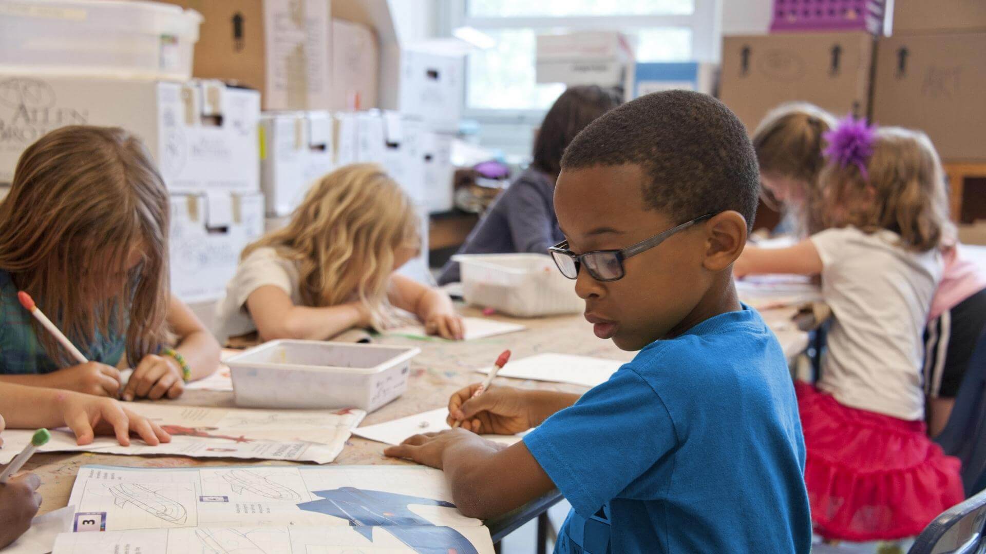 A school child drawing at a desk.
