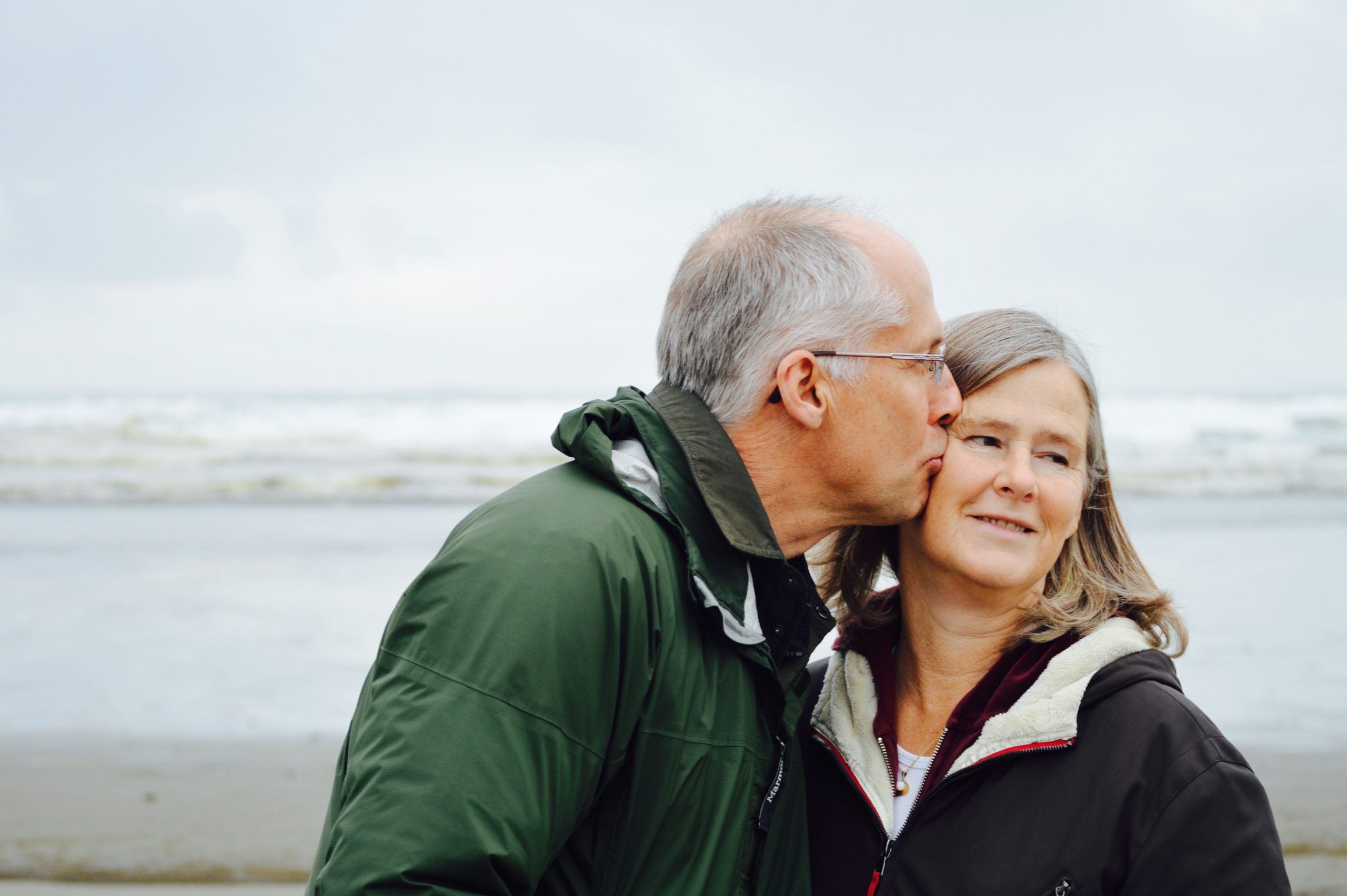 older man kissing wife by lake