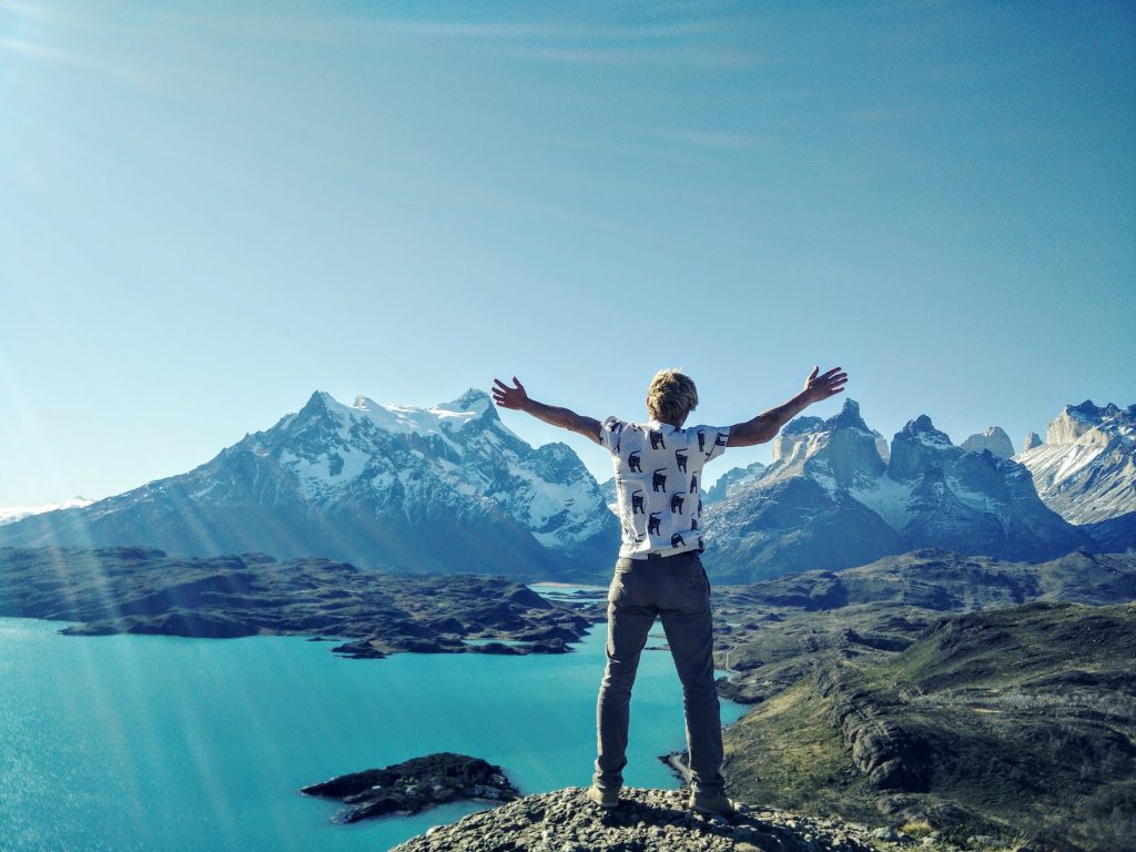 young man with arms raised to mountains