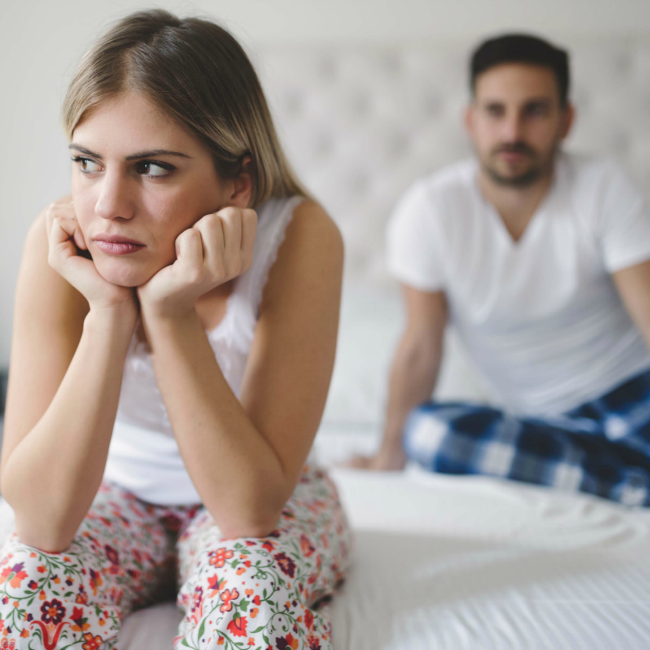 frustrated woman, man sitting behind her in bed