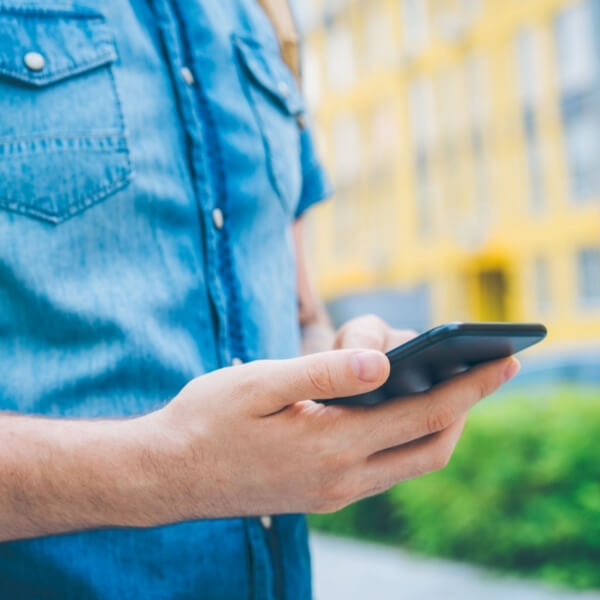 male with phone walking outside