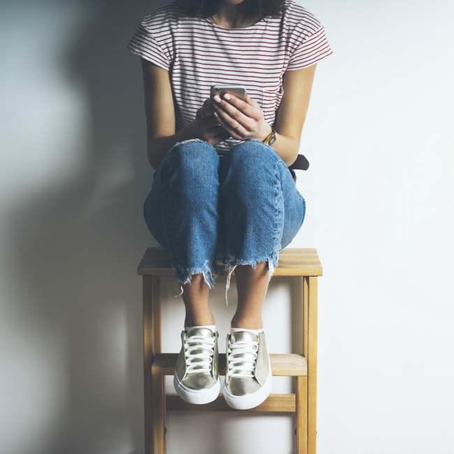 woman sitting on stool watching phone