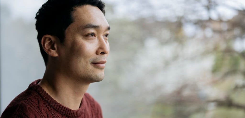 Relaxed man looking thoughtfully out a window.