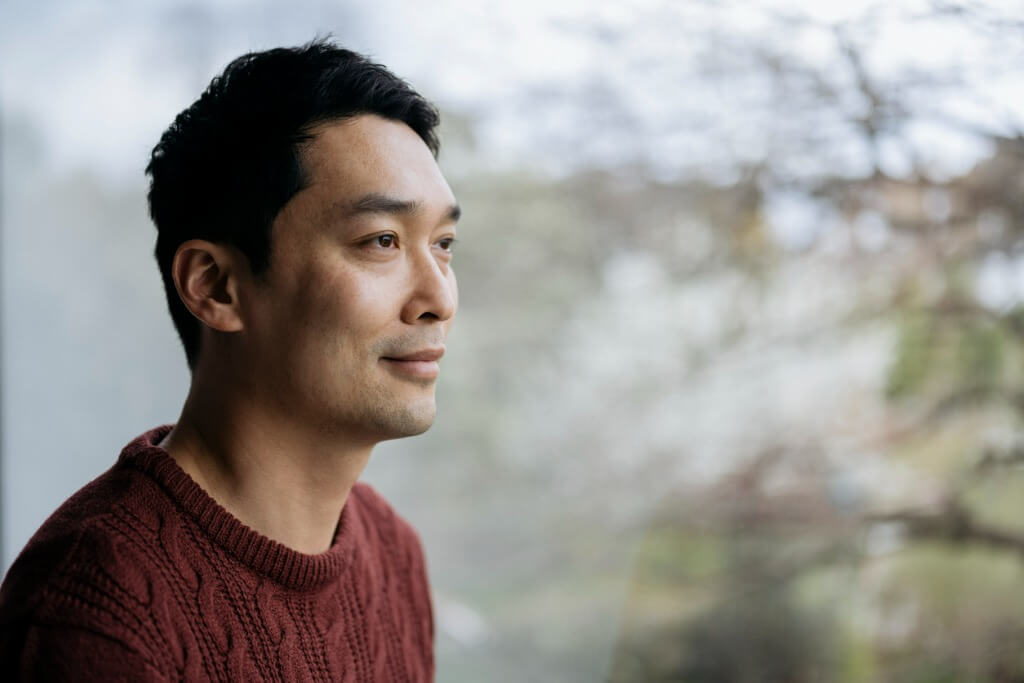 Relaxed man looking thoughtfully out a window.