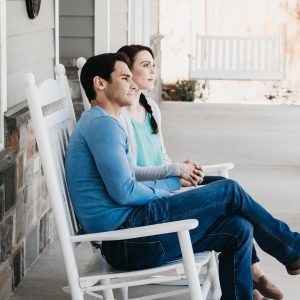 couple holding hands on rocking chairs