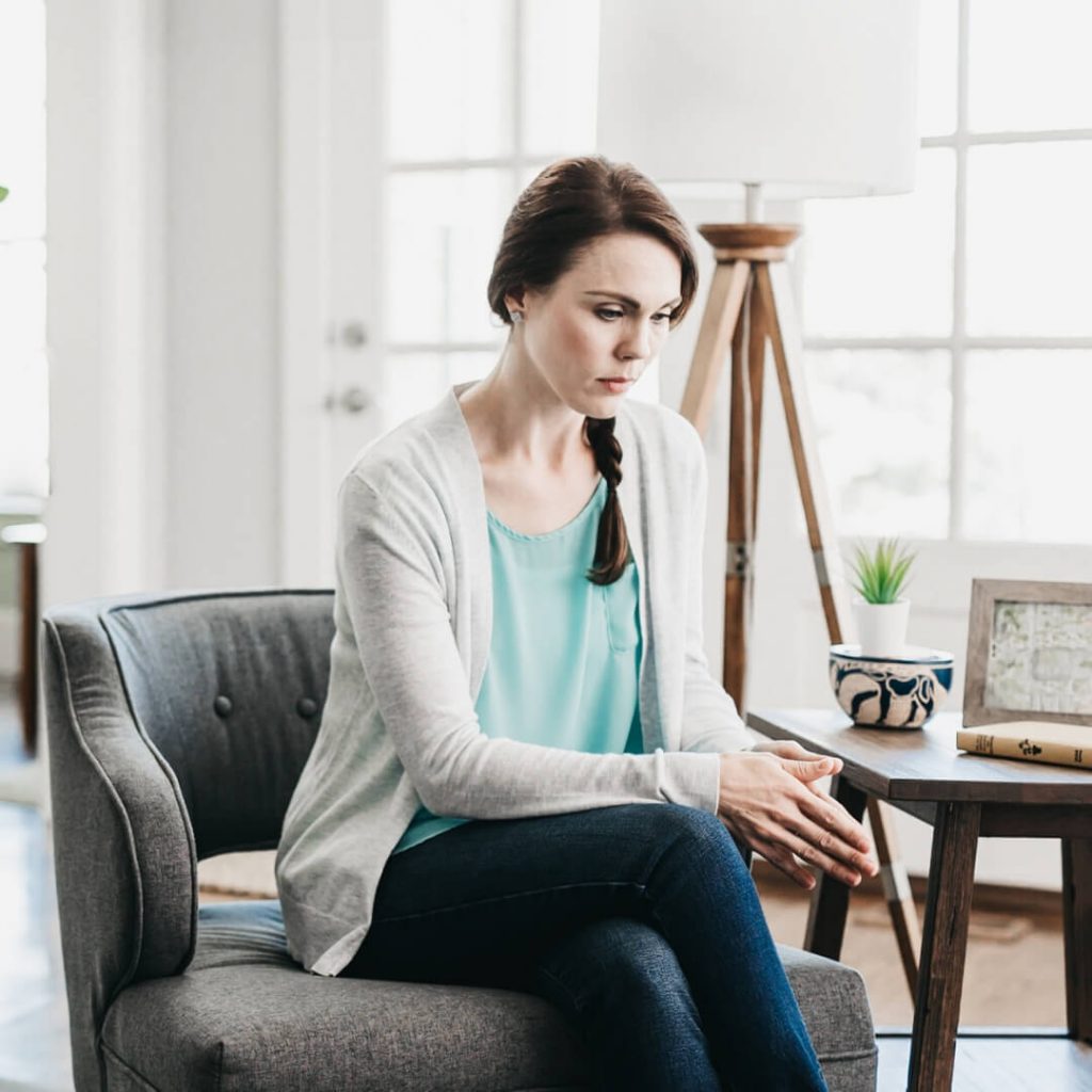 sad woman sitting on chair looking down at floor