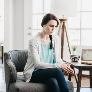 sad woman sitting on chair looking down at floor