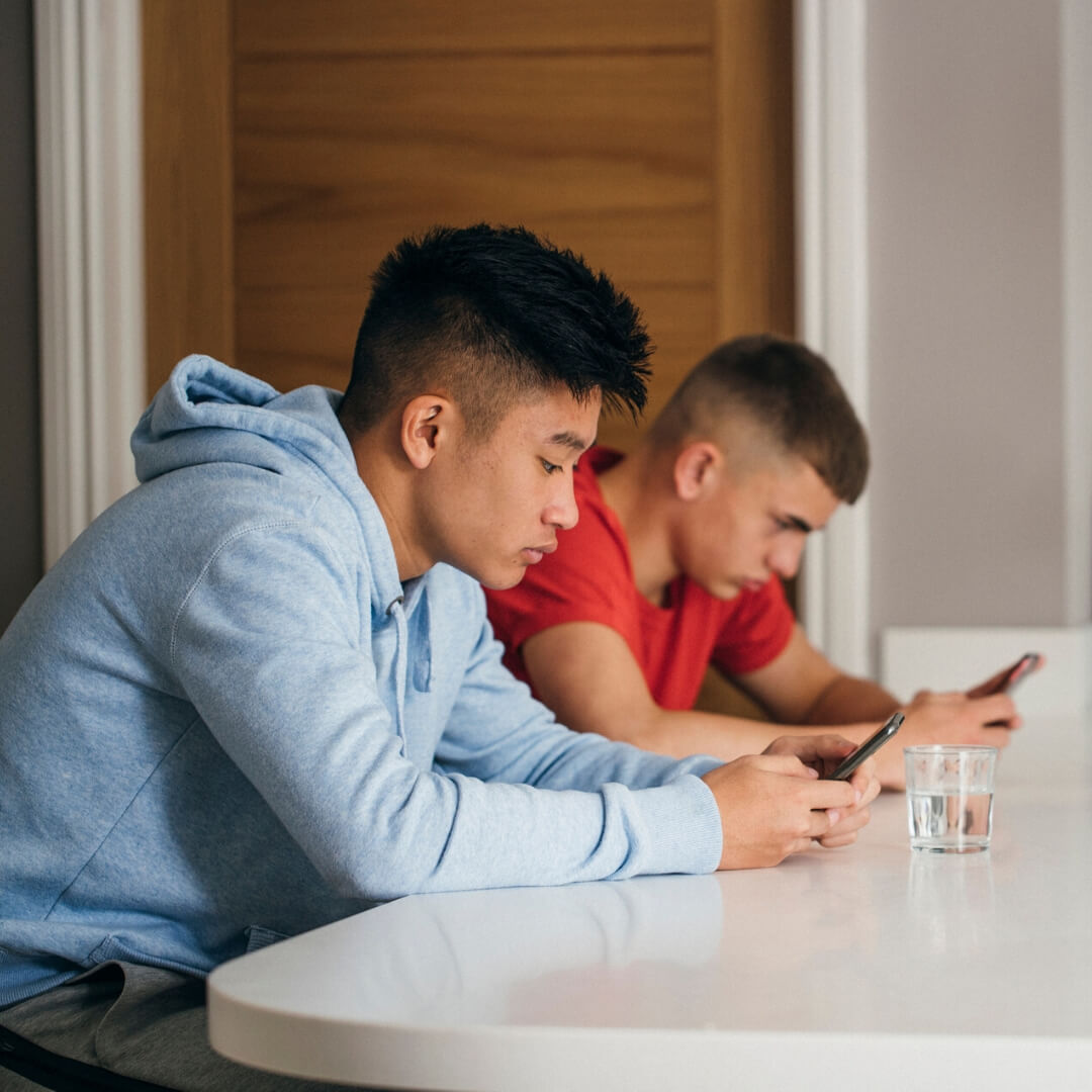teen boys texting at counter