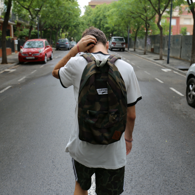 teenage boy walking down street with backpack