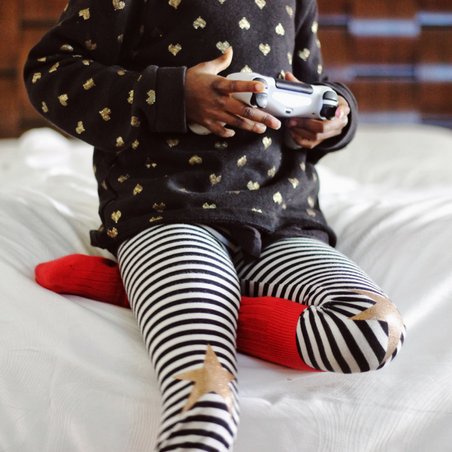 young child playing video games on bed