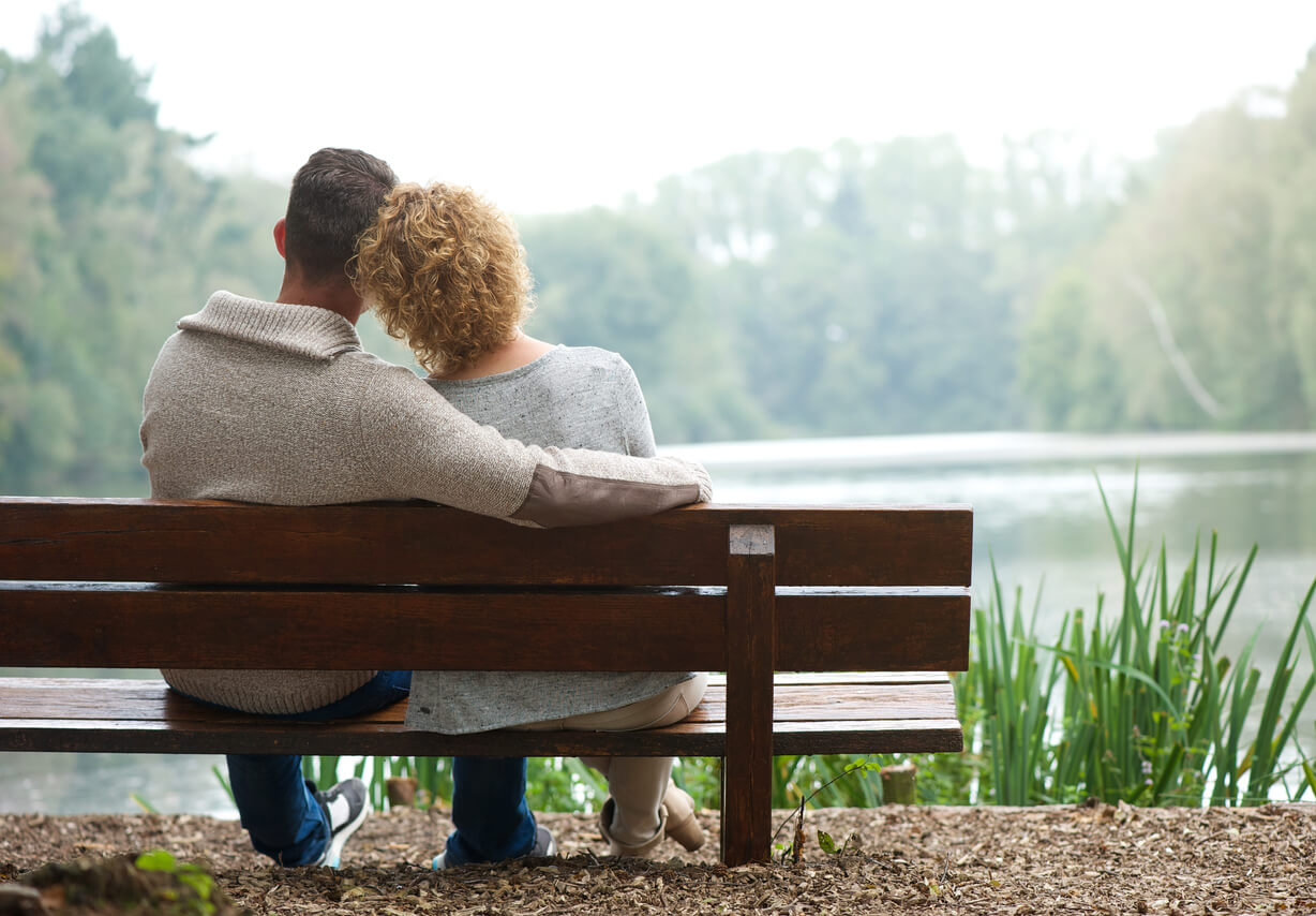 A loving couple outside on a park bench, having a serious conversation about porn.